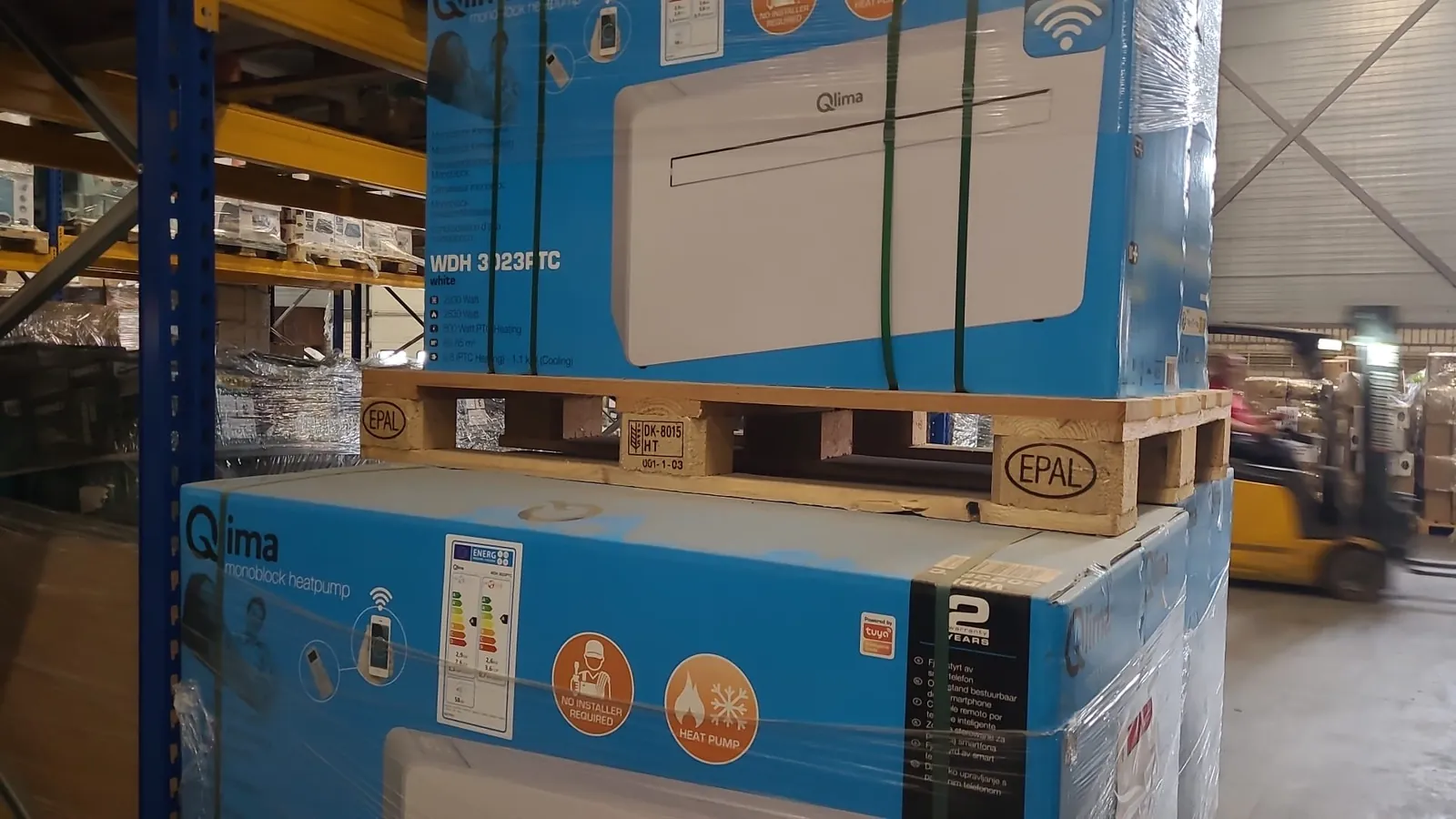 Originalkartons der Qlima WDH 3023PTC auf Paletten in einer Lagerhalle, außen am Karton das EU-Energielabel.